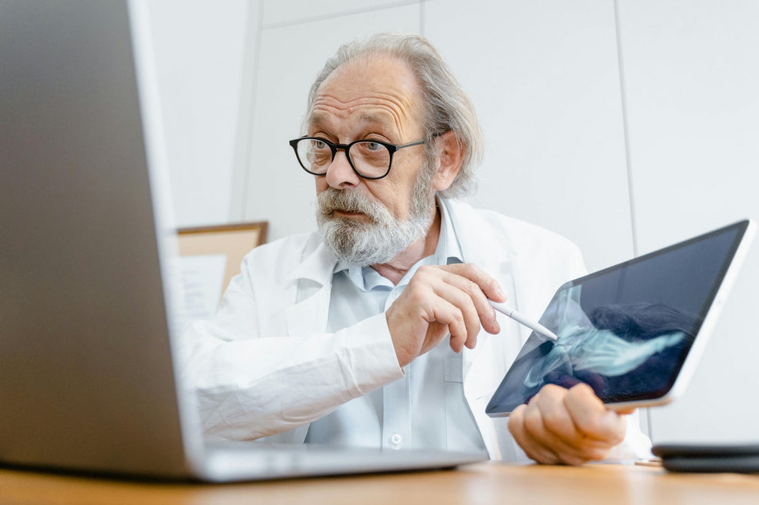 A senior male clinician analyses a bone x-ray on a tablet, discussing the importance of magnesium for bone health and reducing fracture risk