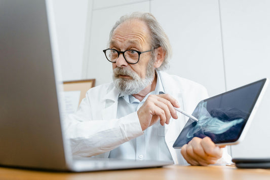 A senior male clinician analyses a bone x-ray on a tablet, discussing the importance of magnesium for bone health and reducing fracture risk