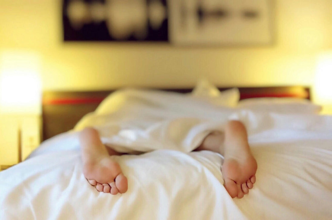 Close-up of a person's relaxed feet in a cosy bed, illustrating how magnesium can improve sleep quality and aid relaxation