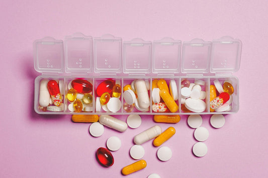 A weekly pill organiser filled with various medicines and supplements, illustrating the importance of managing magnesium interactions for supplement safety