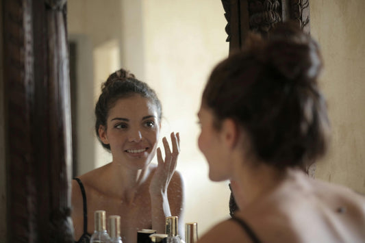 woman with clear skin looking in mirror before going out, representing resveratrol benefits for skin health and beauty
