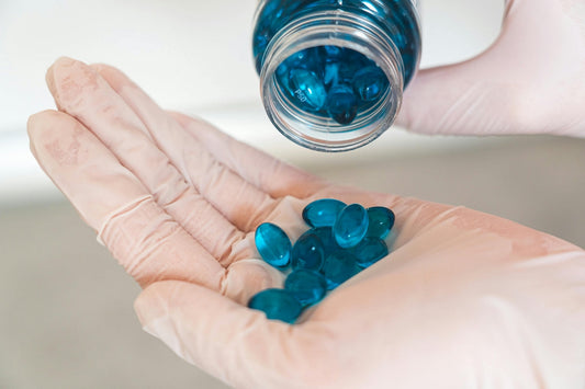 Close-up of gloved hands pouring out many blue magnesium supplement capsules to show the side effects of taking too much magnesium and exceeding the safe dosage